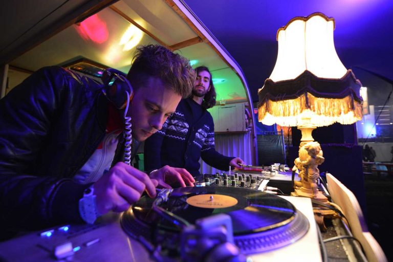 Vinyl DJ buigt zich over een platenspeler naast een schemerlamp