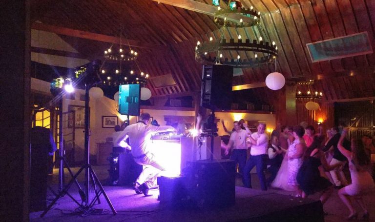 Gasten op de dansvloer voor een DJ show in een zaal met houten balken