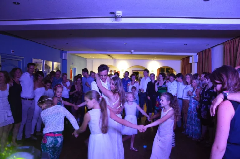 Bruidspaar en gasten met de handen in de lucht op een bruiloftsfeest