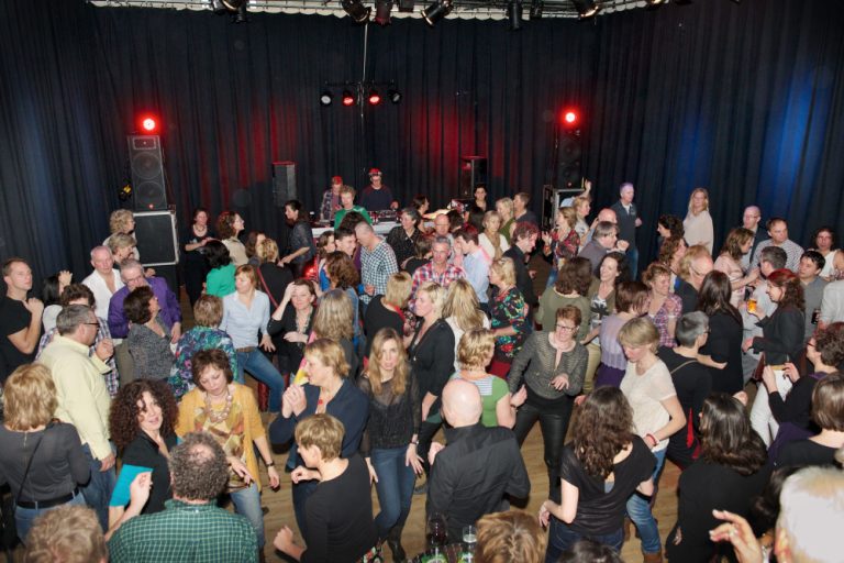 Feestende gasten op de dansvloer voor de DJ booth
