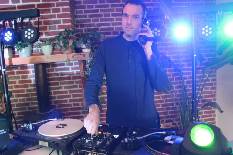 DJ met hoofdtelefoon achter twee draaitafels met een kleurrijke lichtshow