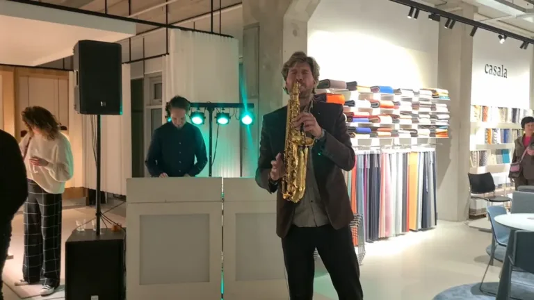 Saxofonist speelt voor een witte DJ booth met groene feestverlichting