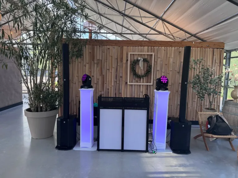 Witte DJ booth met twee paarse lichtzuilen in een lichte kas met houten achterwand